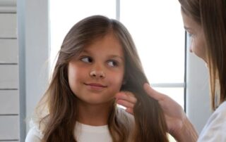 Parent or clinician examining a child’s hair and scalp for early signs of alopecia areata, helping recognize symptoms and determine when to see a doctor.