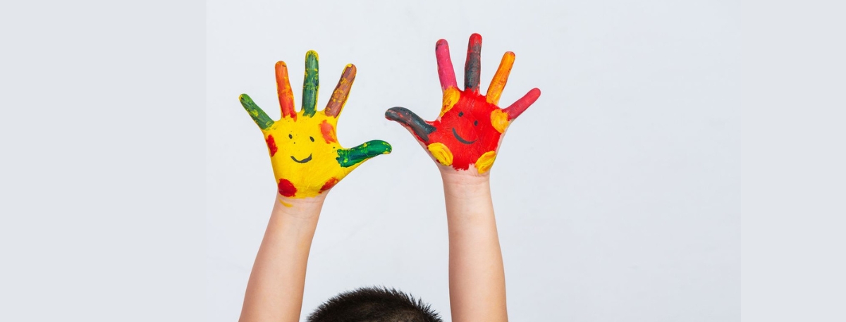 Child raising painted hands, symbolizing early awareness and recognition of plaque psoriasis and pediatric dermatology treatment options.